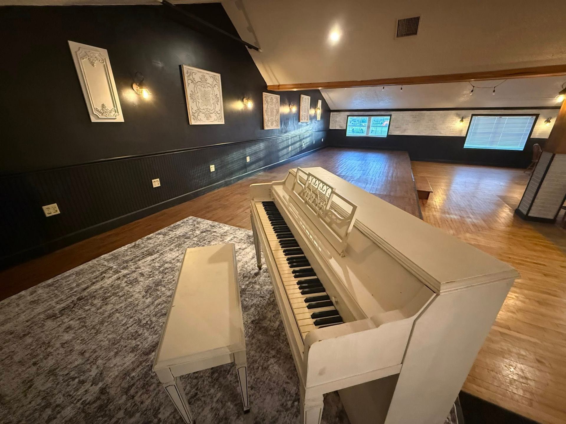 The Piano — White upright, warm rug, string lights at Fields of Grace Farmhouse in Lake Butler, FL
